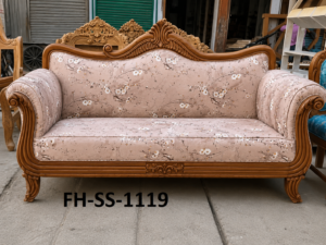 Elegant handcrafted wooden sofa with a blush pink floral upholstered backrest and seat, curved rolled arms, decorative carvings, and a polished natural wood finish.