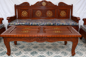 Luxurious handcrafted solid wood sofa set with intricately carved wooden frame, matching carved center table, traditional floral detailing, and premium artisan craftsmanship.
