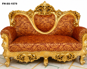 Luxurious handcrafted royal wooden sofa with ornate gold-finished carvings, elegant curved backrest, plush red patterned upholstery, and premium classic craftsmanship.