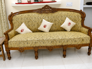 Classic handcrafted wooden sofa with elegant carved frame, premium olive floral upholstery, and decorative accent cushions for luxury living room interiors.