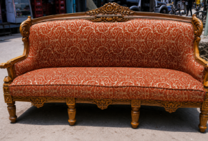 Elegant handcrafted wooden sofa featuring a premium solid wood frame, decorative crown carving, and luxurious red patterned upholstery in a timeless royal design.