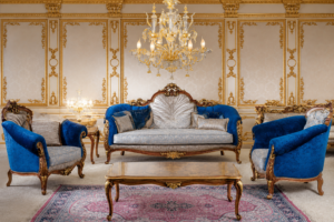 Elegant royal blue and silver luxury sofa set featuring a carved solid wood frame, plush velvet upholstery, matching armchairs, decorative cushions, and a premium wooden center table in a classic palace-inspired living room.