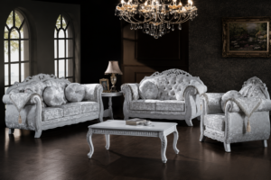 Elegant silver-white luxury sofa set featuring intricately carved solid wood frames, plush tufted upholstery, decorative cushions, matching armchairs, and a classic white coffee table in a premium living room setting.