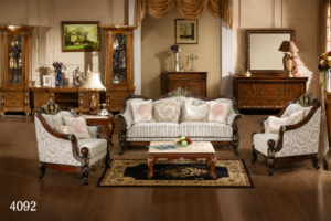 Elegant silver upholstered classic sofa set with dark carved wooden frame, matching armchairs, decorative cushions, and a wooden coffee table displayed in a luxurious traditional living room.