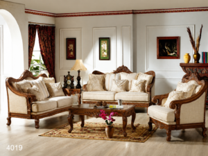 Elegant ivory upholstered sofa set with handcrafted solid wood frame, intricate carved detailing, plush cushions, matching armchairs, and a classic wooden center table in a luxurious living room.