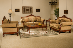 Classic walnut-finished wooden sofa set featuring beige premium fabric upholstery, carved solid wood frame, plush cushions, matching armchairs, and an elegant center table in a sophisticated living room.