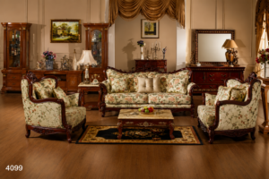Elegant carved wooden sofa set with floral-pattern upholstery, premium cushions, and a handcrafted center table arranged in a luxurious traditional living room.
