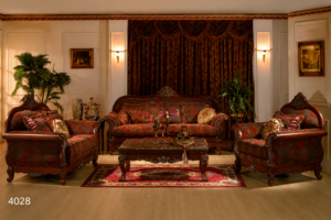 Luxury traditional wooden sofa set featuring deep crimson patterned upholstery, hand-carved solid wood frame, decorative cushions, and matching carved center table.