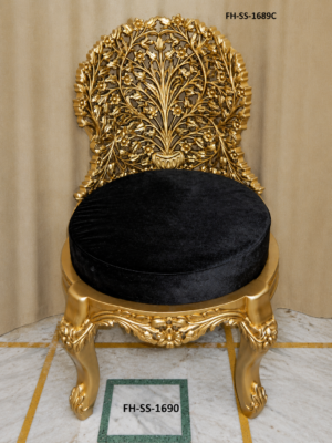 A luxurious handcrafted accent chair featuring an intricately carved gold-finished solid wood frame with an elegant floral backrest design. The plush black velvet round seat adds a sophisticated contrast, making it a stunning statement piece for luxury homes, hotels, lounges, and royal interiors.