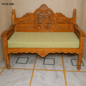 A beautifully handcrafted wooden bench sofa featuring a natural wood finish, intricate floral carvings on the backrest, sturdy armrests, and a comfortable upholstered seat. Its timeless craftsmanship makes it a perfect addition to traditional and contemporary interiors.