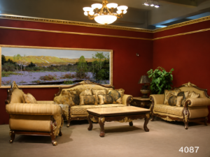Luxury carved wooden sofa set with premium beige upholstery, ornate gold detailing, plush cushions, and a matching center table in a sophisticated classic living room.